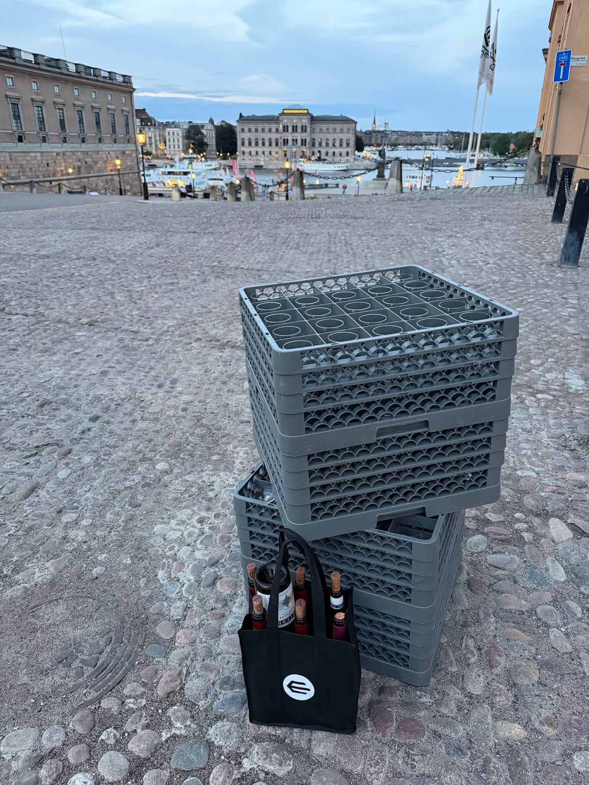 Diskbackar och tomflaskor på kullerstenen utanför lokalen i skymningen, med Skeppsbron i bakgrunden